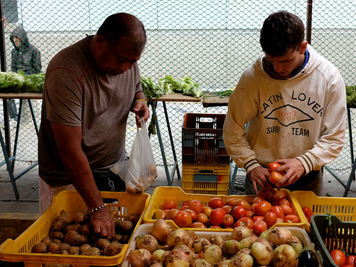 People shop at a vegetables and fruits stall in Caracas.