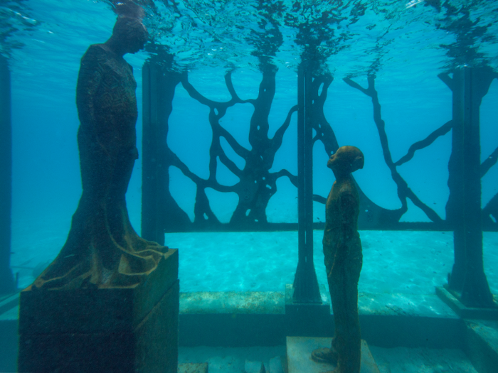 The submerged sculptures include children looking up toward the sea