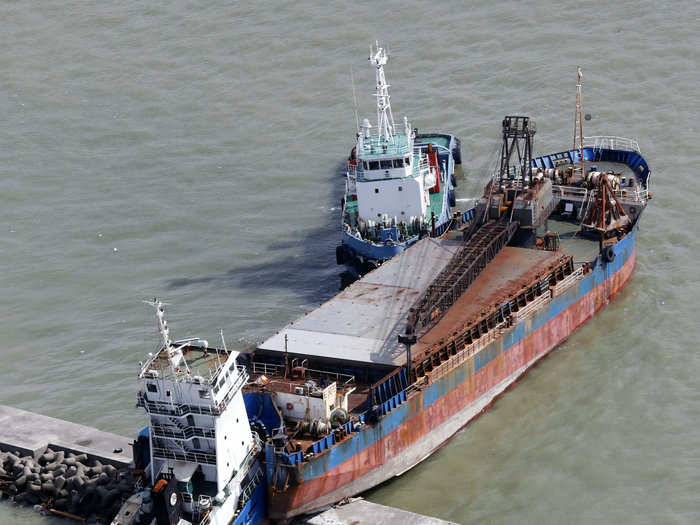 A large commercial ship hit a breakwater, causing shipping containers to spill out into the sea.