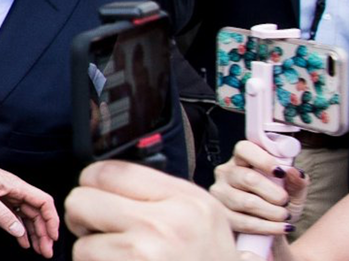 While Mr. Casio Watch is filming the scene, a woman next to him, with a pink phone and pink selfie stick is filming...the scene or herself, it