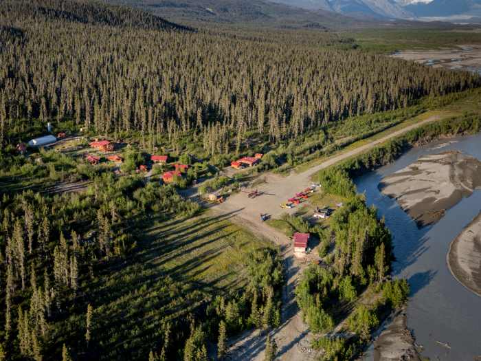 Flying in, guests get a clear aerial view of the lodge and cabins, which are set in a clearing surrounded by forest and facing the Chitina River.