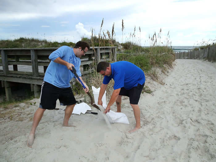 Vulnerable residents got plywood and sand bags to protect their properties, like these North Carolina residents who gathered sand from the beach Tuesday morning as the hurricane was set to make landfall over the state.