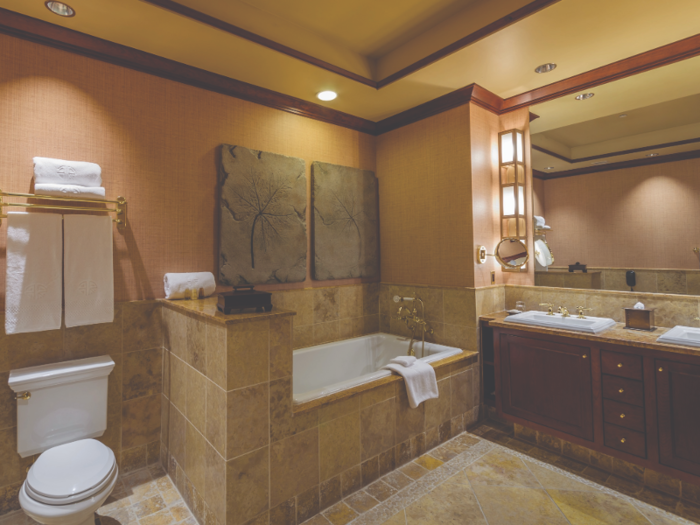 The marble bathroom includes a 200-gallon soaking tub, a separate glass shower with a multi-setting European shower head, and luxury bathrobes and slippers.