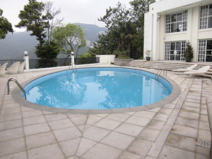 Views of the hilly, greenery-filled neighborhood surround the pool area.