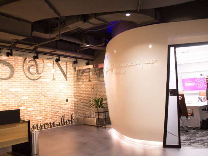 Sitting next to the reception desk is a white room built for video conferencing and meetings. Inside, the space design is white and minimalistic, and the wall on the far facing end holds two large screens along with motion sensing cameras.