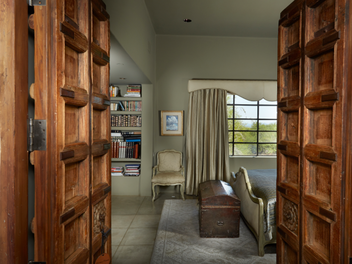 Tucked away behind heavy wooden doors, the master suite has its own private library.