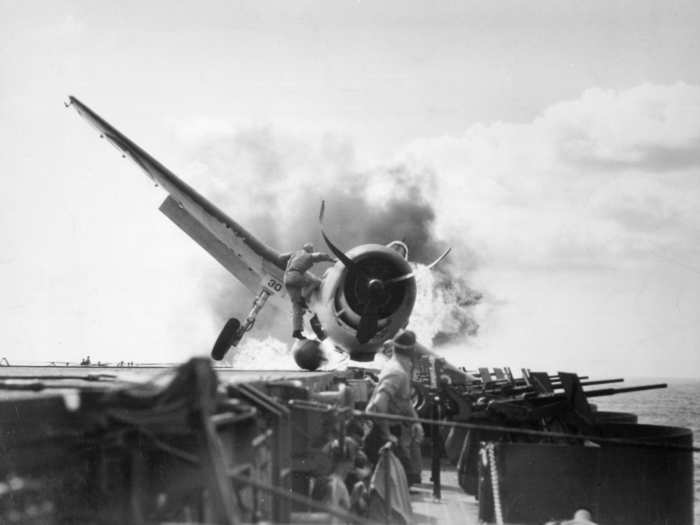 Lt. Walter L. Chewning Jr. climbs up a F6F Hellcat to help pilot Ensign Byron M. Johnson, who crash-landed on the Enterprise