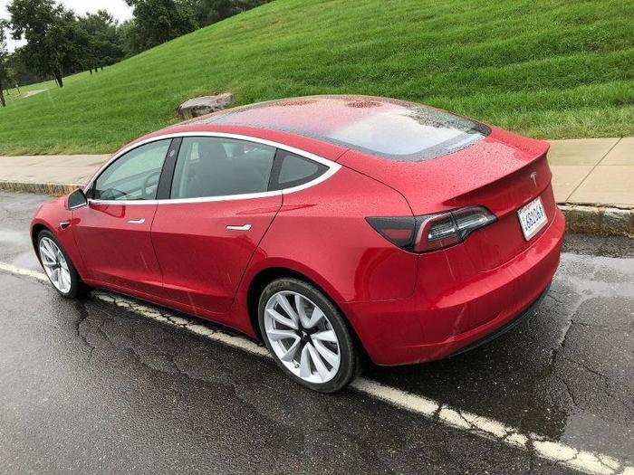 The entire roof is a continuous curve of glass, with a fastback rear hatch/trunk culminating in a crisp spoiler. The recessed door handles and the window trim are the only significant chrome on the Model 3.