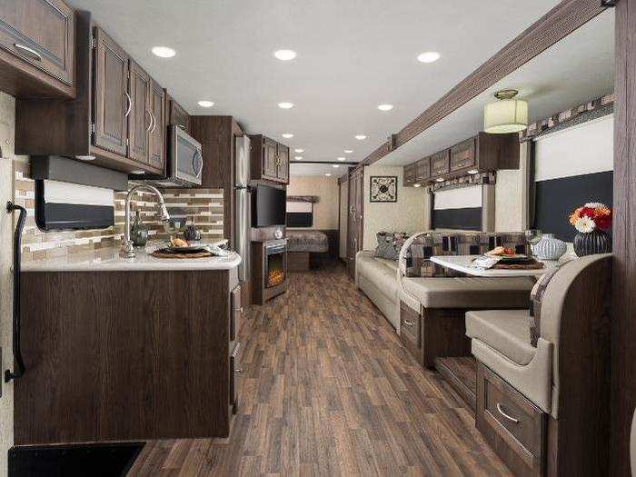 The Coachmen Mirada interior features an eight-cubic-foot double-door refrigerator, brushed nickel hardware, glass shower door, and vinyl flooring.