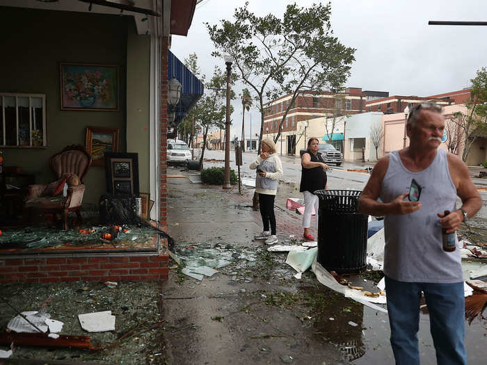 People walk past damaged stores after Hurricane Michael.