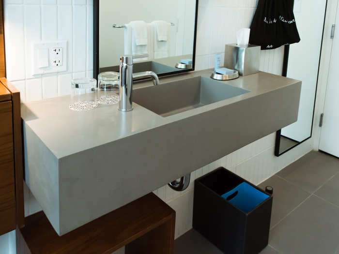 From the entryway, the toilet and shower are enclosed behind opaque glass to the left. The sink is to the right.