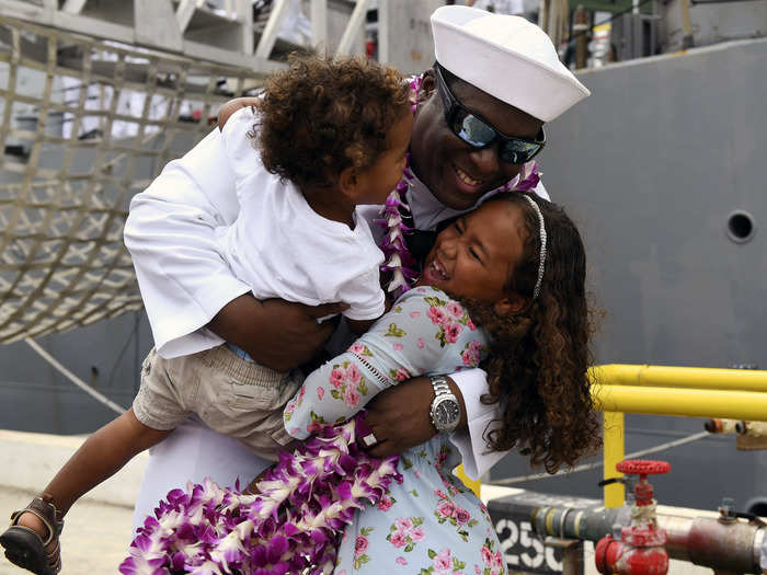 Fire Controlman 1st Class Kial Hartwell is greeted by his children during the homecoming ceremony for the guided-missile destroyer USS O