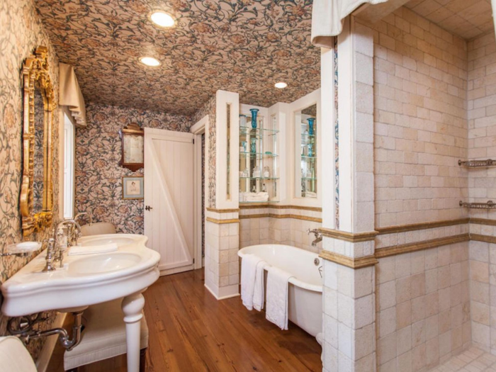 Another bathroom has a clawfoot tub as well as wallpaper along its walls and ceiling.