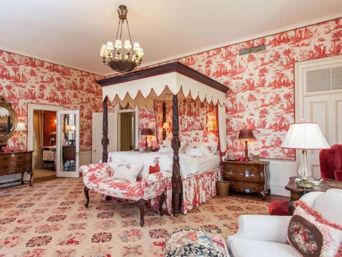 Another bedroom is decorated in shades of red and pink with an elegant canopy ...