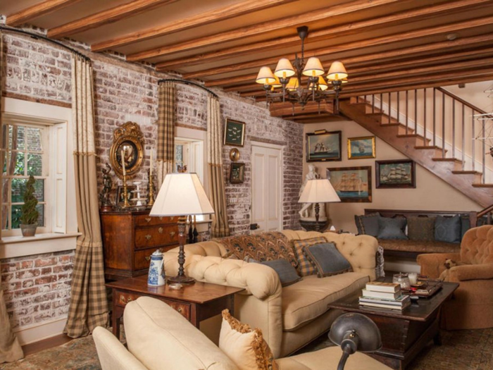 The living room inside has brick walls and beamed ceilings.