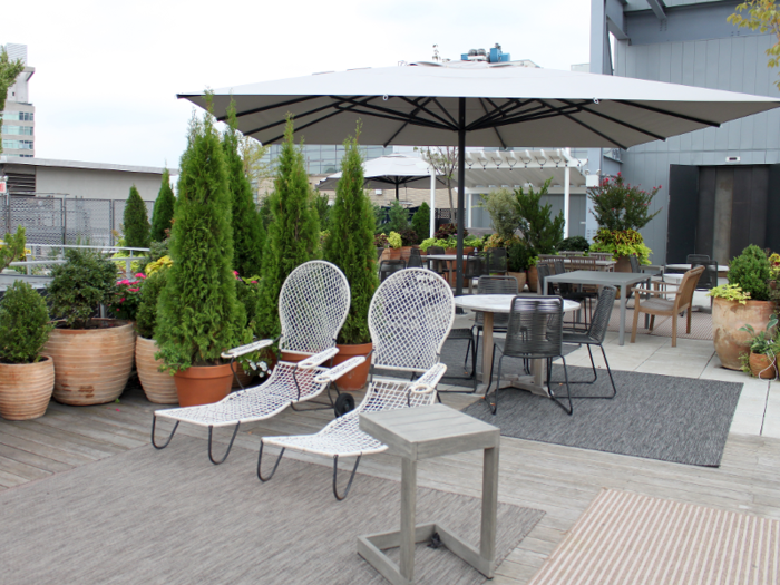 The rooftop was full of lounge chairs, large plants, and small tables shaded by umbrellas.