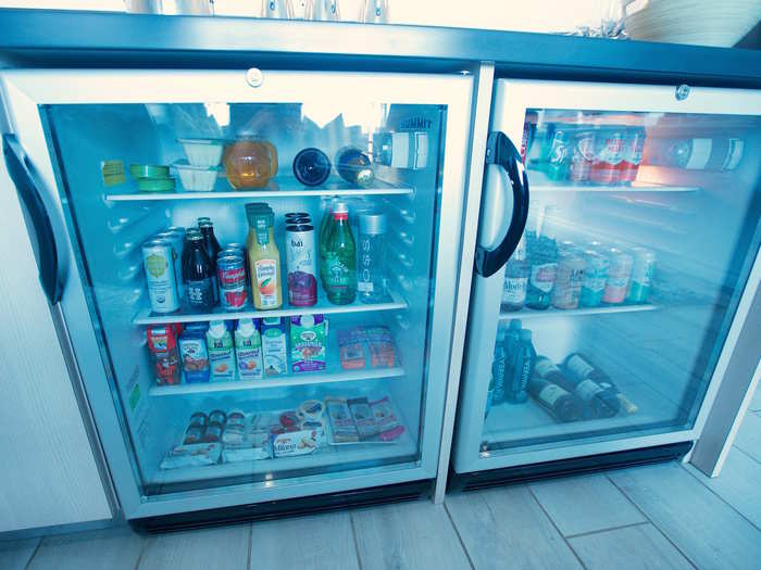 The mini fridge is stocked with bottles of white wine and champagne, along with various non-alcoholic beverages. Travelers can request a bottle of red wine, too.