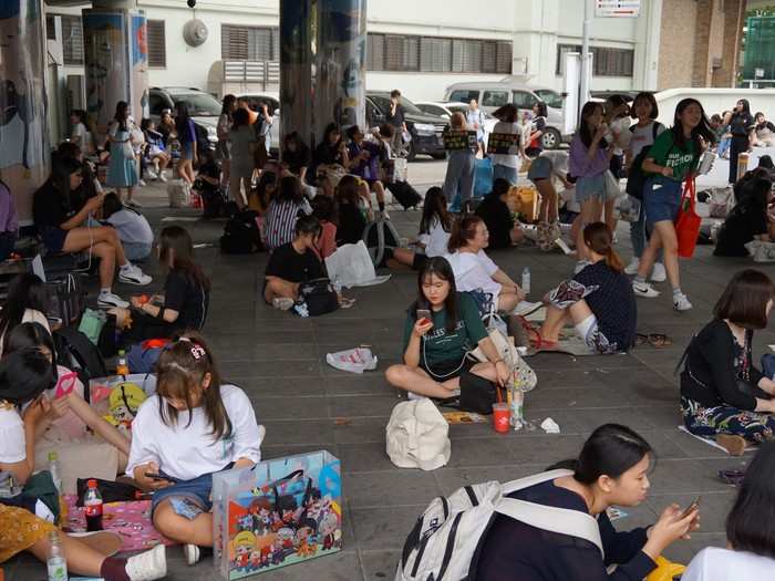 Wherever I looked, the place was filled with fans who had set up base outside. Some were practicing the lyrics to the group’s new single, “IDOL,” which had been released less than 24 hours prior. Others were applying makeup, and some were rummaging through their suitcases.