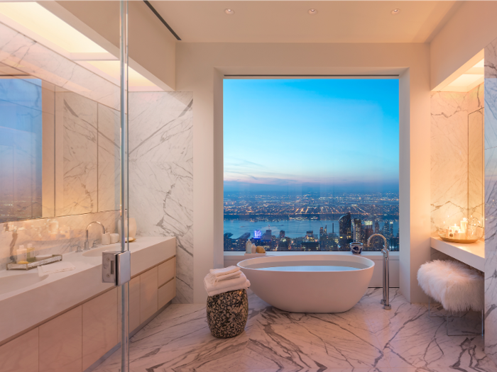 The luxurious master bathroom has marble floors and walls, cubic marble vanities with 22-inch oval sinks, custom wood cabinets, a large freestanding soaking tub, shower, Toto toilet, radiant heated floors — and eye-popping views of the city.