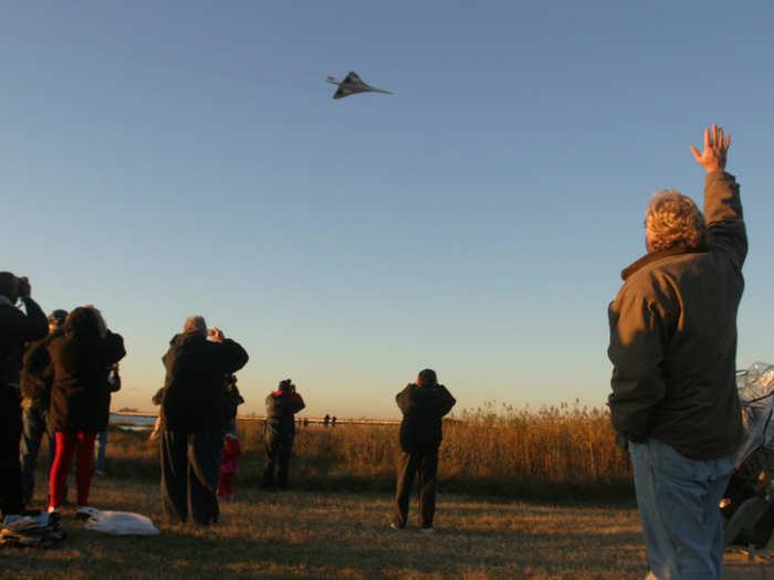 Onlookers wave goodbye to the Concorde as it climbs out of JFK Airport.