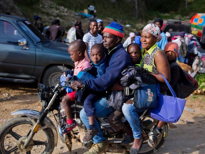 Some Haitian commuters squeeze on motorcycles to travel.