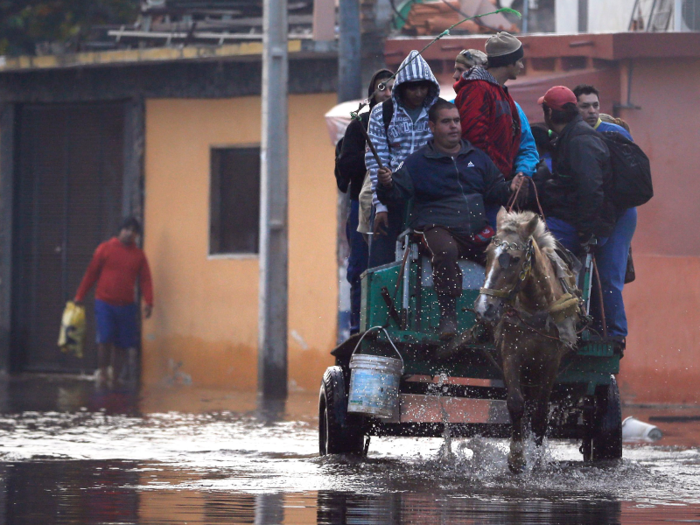 Flooded streets in Asuncion, Paraguay, prompt commuters to use horse-drawn wagons.