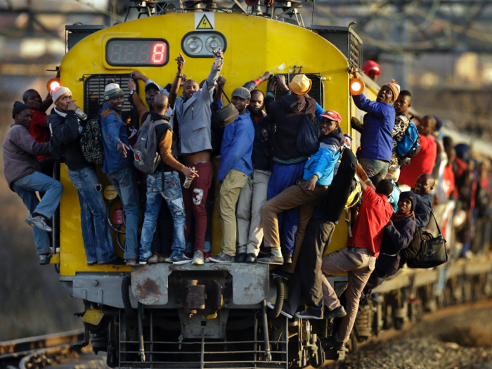 Commuters also hold onto the side of trains in Soweto, South Africa.