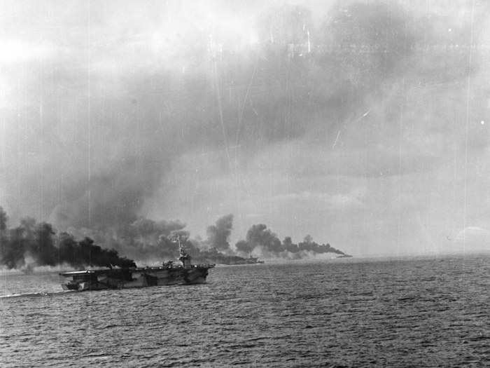 The USS Gambier Bay billowing smoke after likely getting struck by Japanese cruisers, which are credited with sinking the US escort carrier.