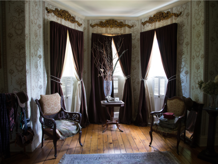 Gold sconces hang above bay windows framed by burgundy drapes.