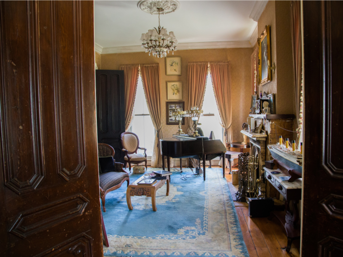 One of the front parlors bears a piano and seating for entertainment.