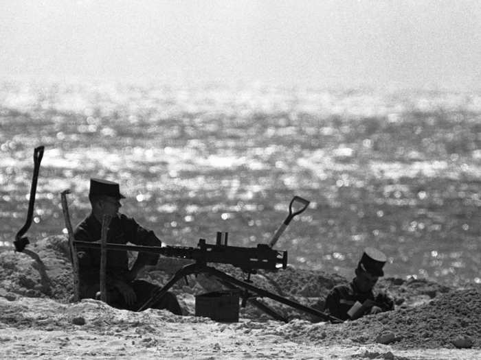 Two soldiers sit in a sandy dugout beside a machine-gun position on a beach at Key West, Florida, October 27, 1962.