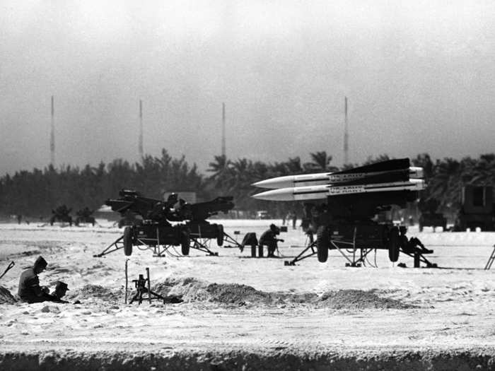 Two soldiers sit in a machine-gun emplacement beside anti-aircraft rocket positions on a beach at Key West, Florida, October 27, 1962.