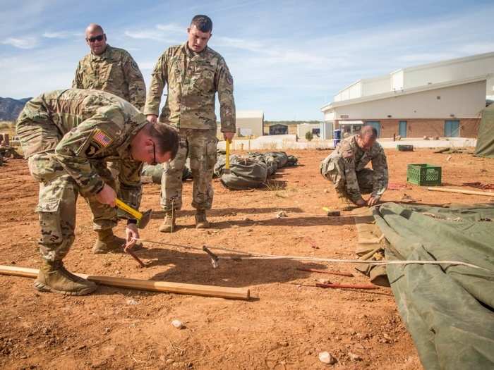 A US Army soldier assigned to 309th Military Intelligence Battalion hammers a stake into the ground while setting up tents at Fort Huachuca, Arizona on Nov. 1.