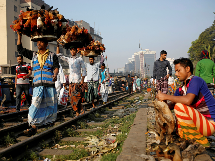 Some vendors walk along train tracks selling goods.