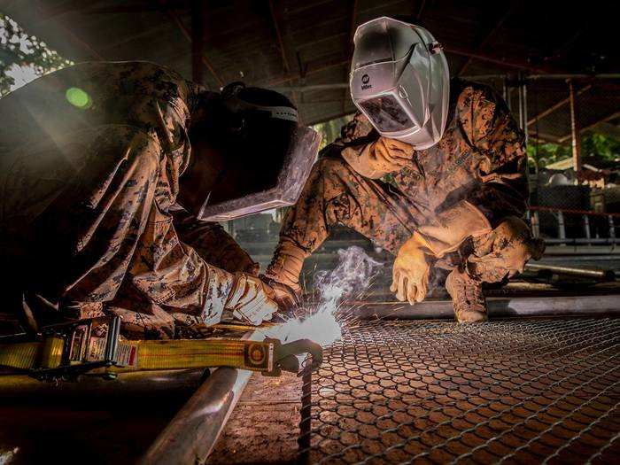 Marines with SPMAGTF-SC weld a fence to provide security while rebuilding a school in Flores, Guatemala on Aug. 6, 2018.