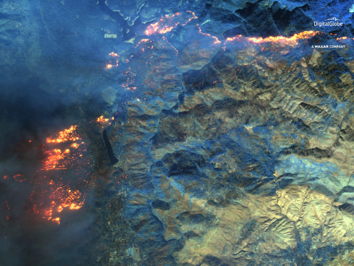 Healthy vegetation is shown in blue, active fires glow, and scorched areas look yellow-green and yellow-orange. The town of Paradise is in flames to the left in this picture.