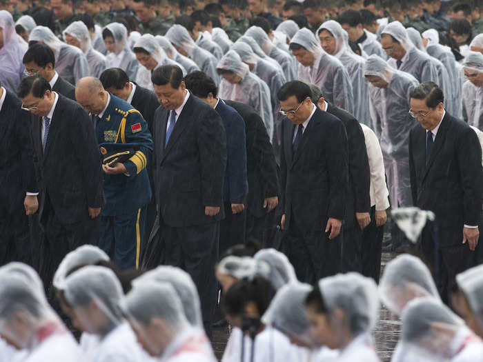 Chinese President Xi Jinping bows in the rain at the Monument to the People