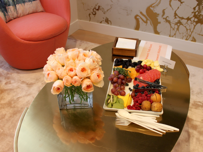 Fresh flowers, bite-sized healthy snacks, and pitchers of water were set out on golden coffee tables.