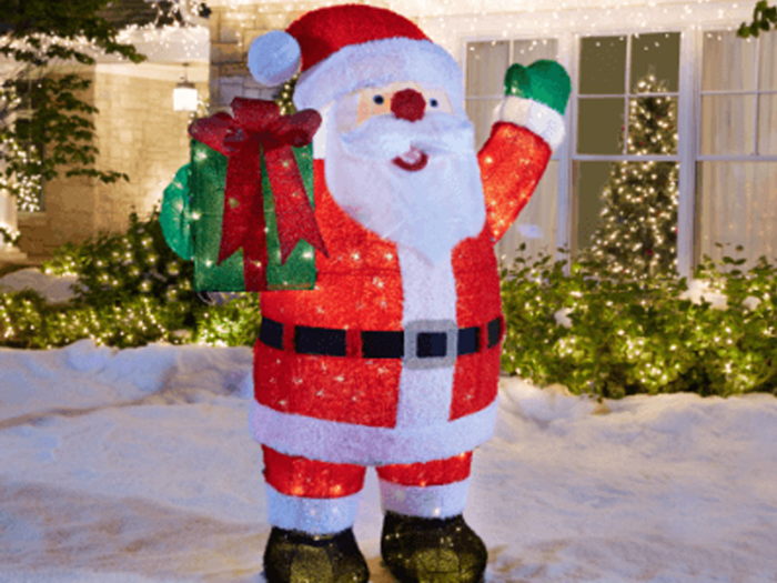 A giant cheery Santa Claus holding a gift box