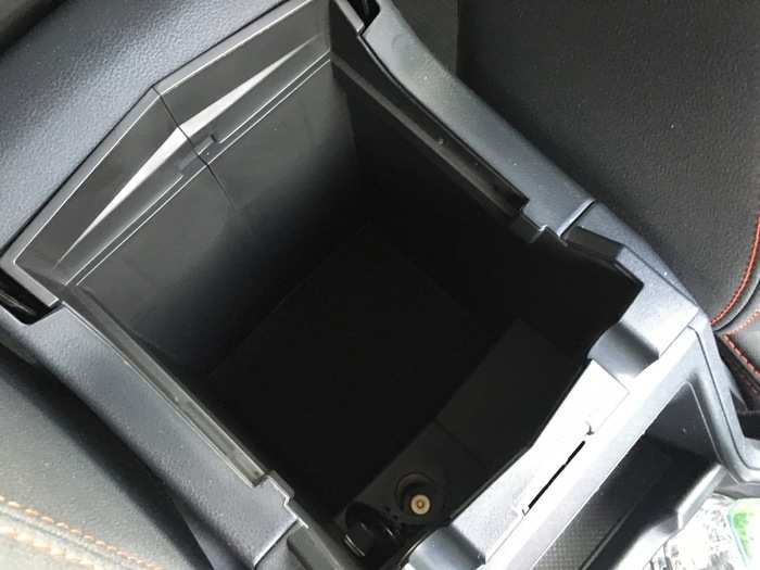 Under the armrest, there is a sizable storage bin with an additional power plug.