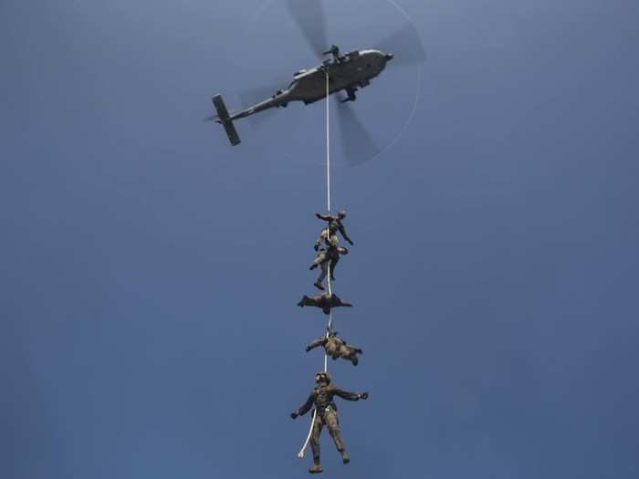 Dangling from a helicopter in the air.