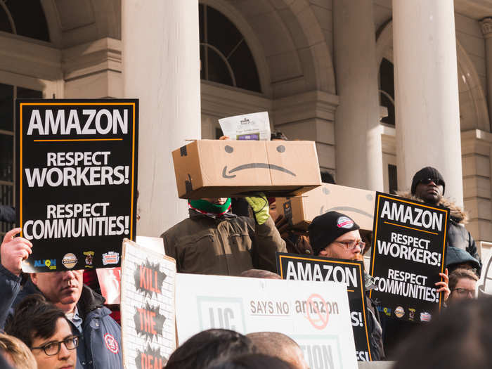 Other signs read, "Stop Amazon" and "Amazon: Respect workers! Respect communities!"