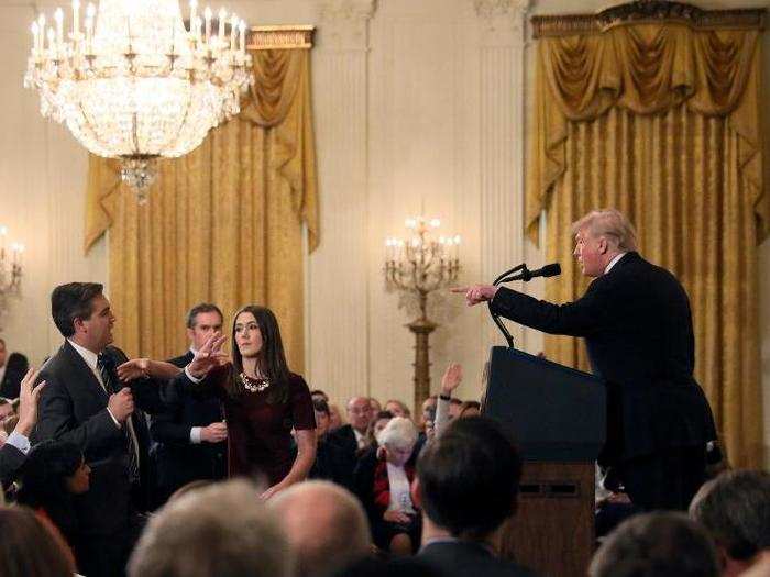 A White House staff member reaches for the microphone held by CNN