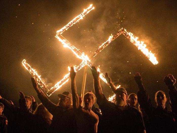 Supporters of the National Socialist Movement, a white nationalist political group, give Nazi salutes while taking part in a swastika burning.