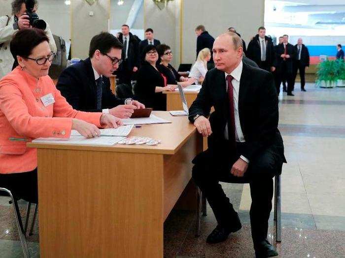 Russian President and presidential candidate Vladimir Putin waits to get his ballot as he arrives to vote at a polling station during Russia