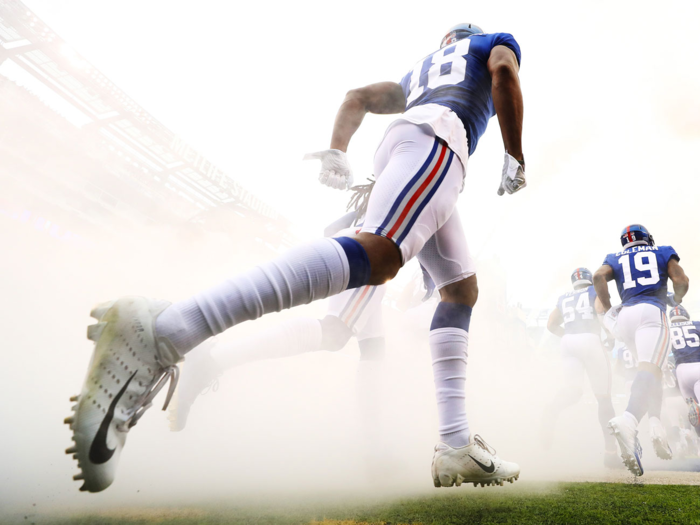 The New York Giants emerge from a cloud of smoke to take the field.