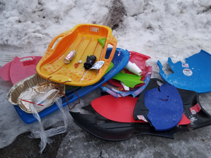 Broken sleds and discarded beer cans line the snow-covered ground.