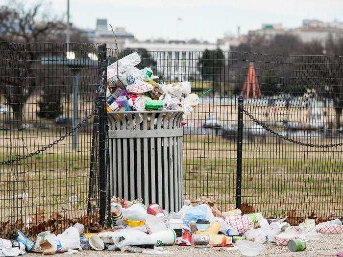 The White House can be seen behind an overflowing trash can.