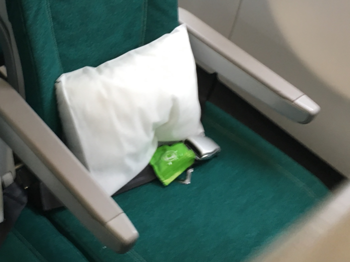 At our seat, we find a pillow and a pair of earbud headphones.