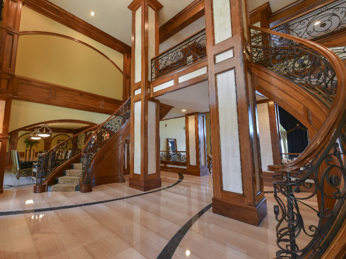 The grand foyer features double, curved grand staircases and polished marble floors.